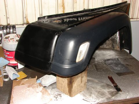 1993 Jeep Wrangler - A black Jeep fender is shown in a workshop setting, supported by wooden blocks.