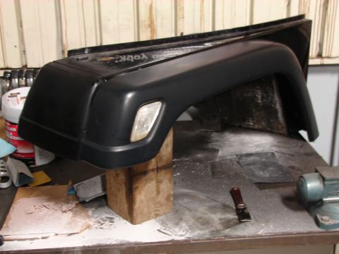 1993 Jeep Wrangler - A black Jeep fender flare is shown on a workbench, possibly undergoing restoration or repair.
