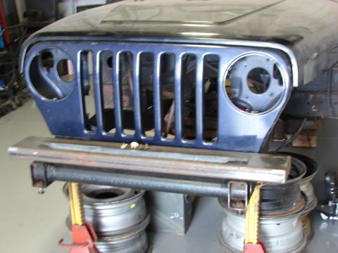 1993 Jeep Wrangler - Front view of a 1993 Jeep YJ grille and hood assembly, supported by jacks and tires.
