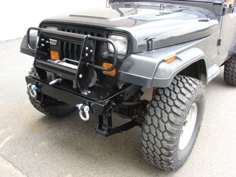1993 Jeep Wrangler - Front view of a black Jeep with a winch and brush guard, equipped with off-road tires.