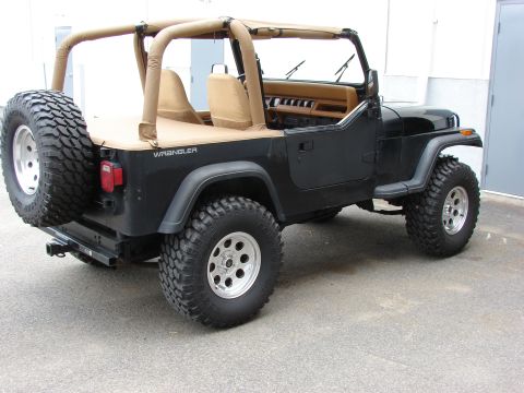 1993 Jeep Wrangler - Black 1993 Jeep YJ Wrangler with tan soft top and spare tire on rear bumper.