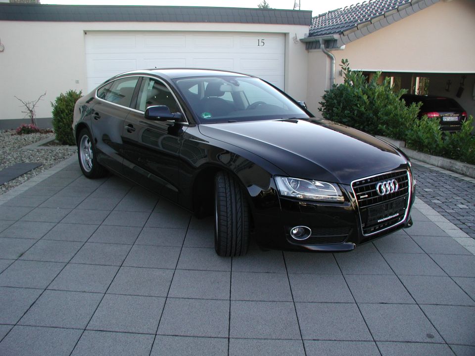 Black Audi A5 Sportback parked on a tiled driveway in front of a garage