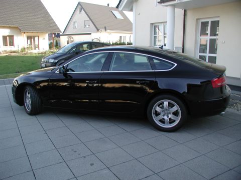 2010 Audi A4 - A black sedan is parked on a tiled driveway in front of a house, with another vehicle visible in the background.