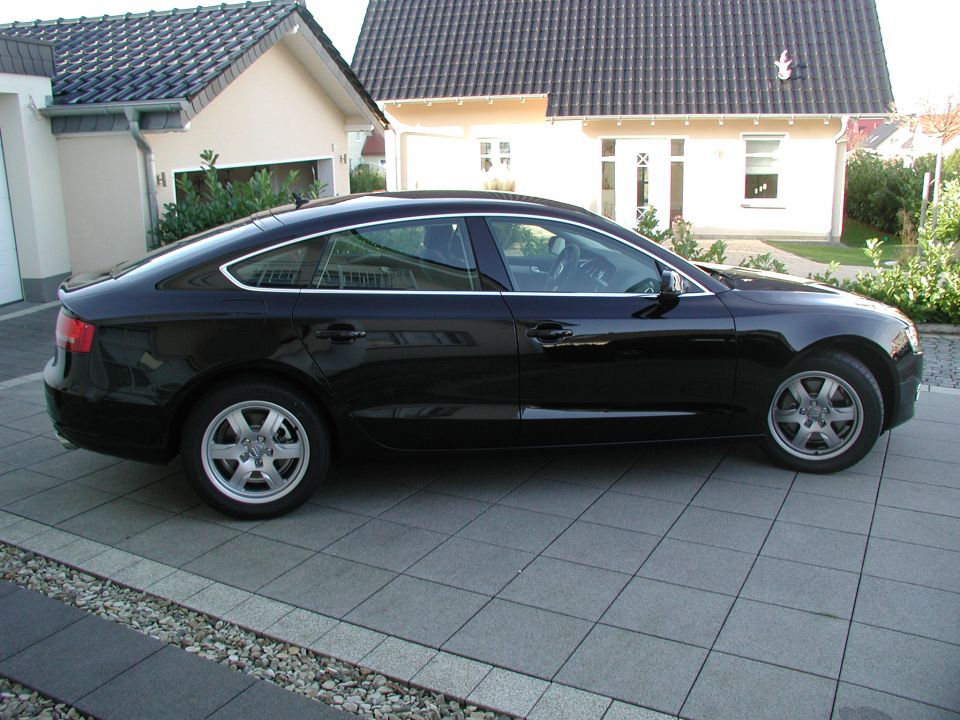 Black Audi A5 Sportback parked on a tiled driveway in front of a house