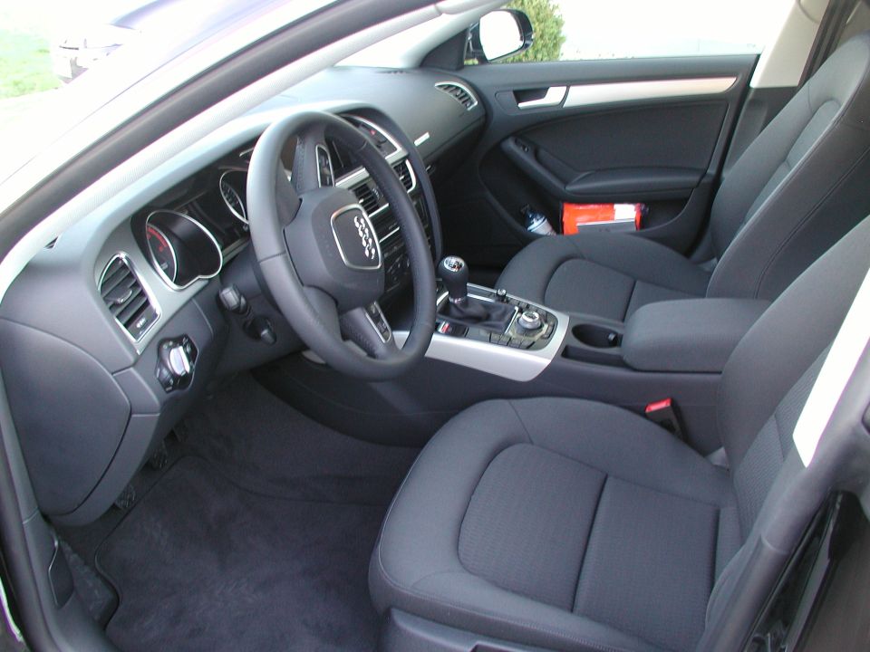 Black Audi car interior showing steering wheel, dashboard and manual shifter