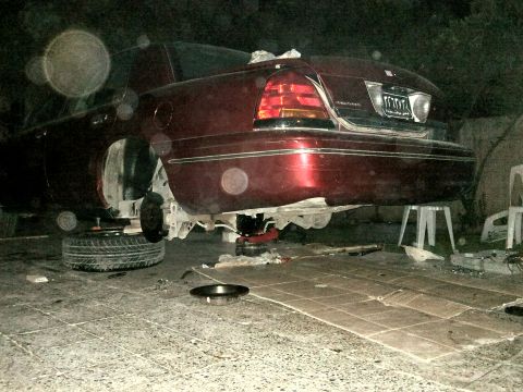 1998 Ford Crown Victoria - A maroon 1998 Ford Crown Victoria is shown from the rear, elevated on jacks for maintenance.