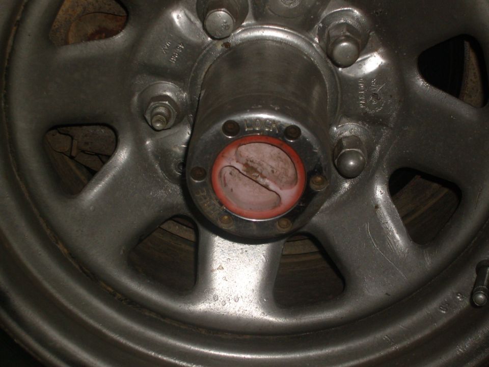 Close-up of a metal wheel hub with red locking mechanism. Text 'LOCK' is visible