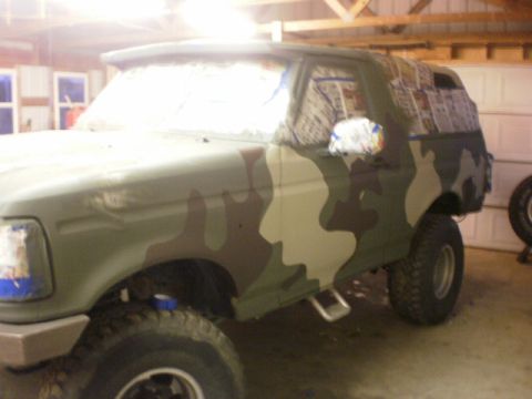 1995 Ford Bronco - A Ford Bronco is being painted with a camouflage pattern inside a garage.