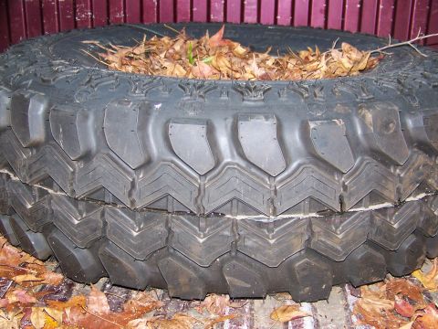 1992 Jeep YJ - A close-up view of a large tire filled with fallen leaves, suggesting it is not currently mounted on a vehicle.
