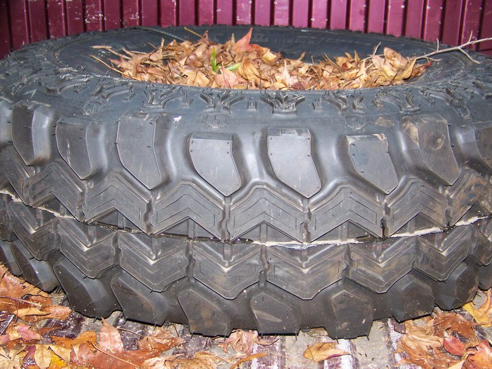 Tire with deep treads filled with dry leaves, resting on the ground