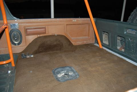 1982 Ford Bronco - The rear interior of a vehicle, brown carpet and an orange roll cage, is visible.