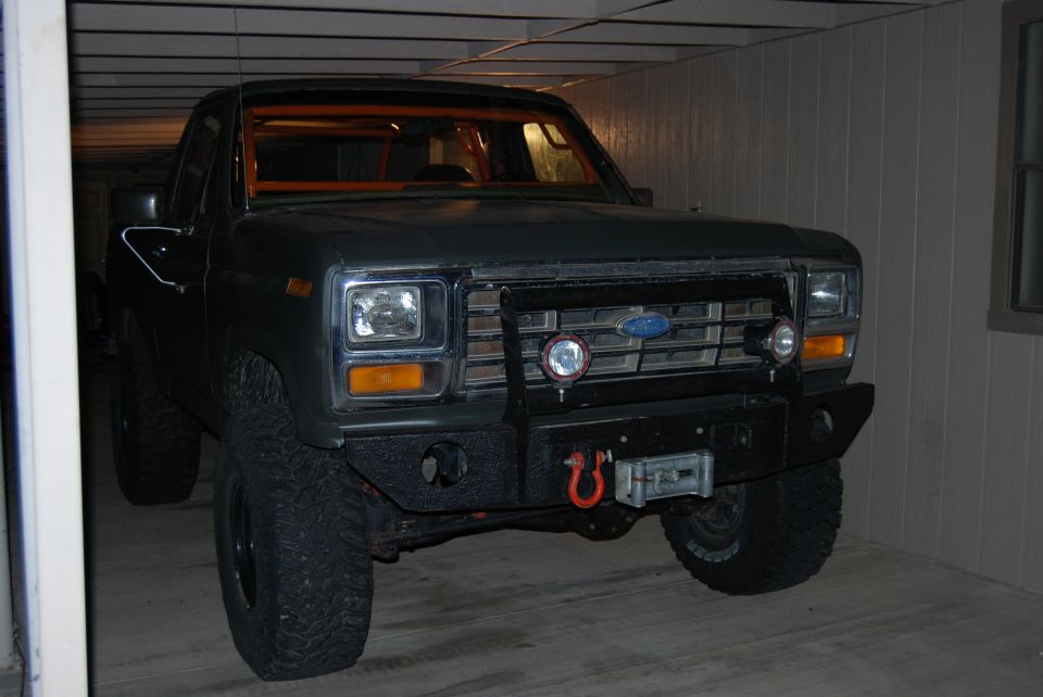 Dark gray Ford truck with orange roll cage, aftermarket bumper, and winch