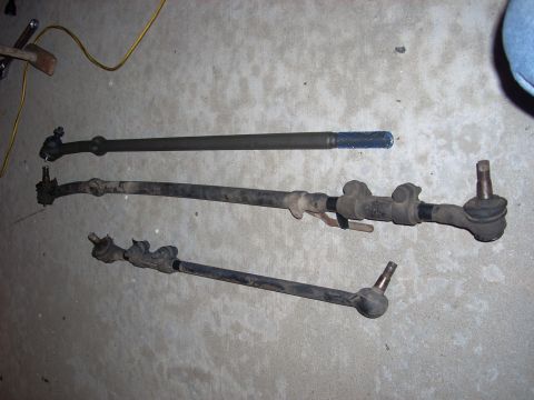 1989 Ford Bronco - Various steering linkage components are displayed on a garage floor.