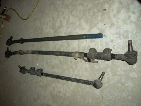 1989 Ford Bronco - Various steering linkage components are laid out on a concrete surface.
