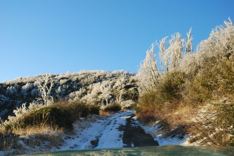 1996 Ford Bronco - A snowy mountain road with frosted trees and a clear blue sky. Supermotors watermark visible.