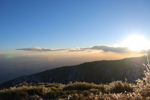 1996 Ford Bronco - A vast mountain landscape is illuminated by the rising sun, with clouds obscuring the horizon and frost covering the vegetation.