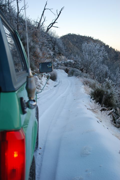 1996 Ford Bronco - A green SUV drives on a snowy mountain road during winter.