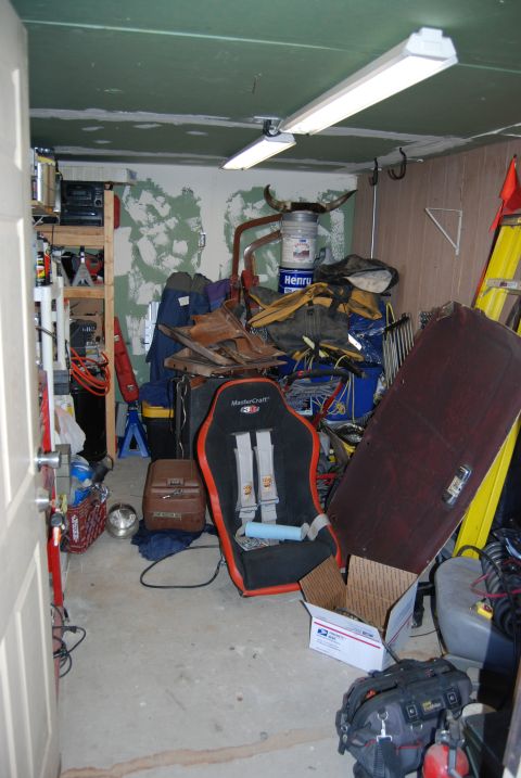 1982 Ford Bronco - A cluttered garage interior scene features a racing car seat, various storage items, and a yellow ladder leaning against the wall.
