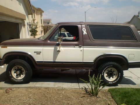 1982 Ford Bronco - A two-tone Ford Bronco is seen from the side, parked in front of a house.