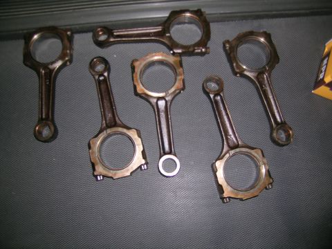 1995 Ford Probe - Several engine connecting rods are displayed on a textured surface, with a partial box visible in the background.