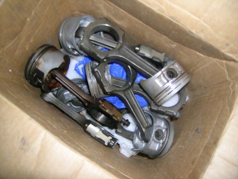 1995 Ford Probe - A collection of engine pistons and connecting rods are piled inside a cardboard box.