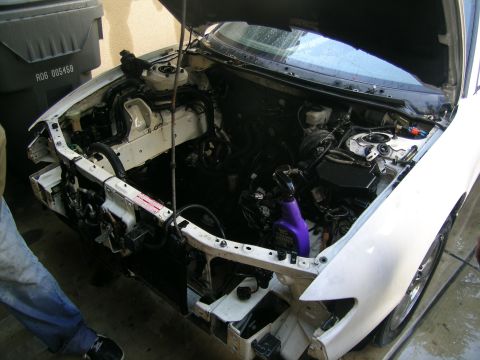 1993 Ford Probe - The front end of a white car has been disassembled, revealing the engine and its associated parts.