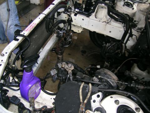 1993 Ford Probe - The engine bay of a vehicle is shown with the radiator and extensive wiring. Tools and a spray bottle are present.