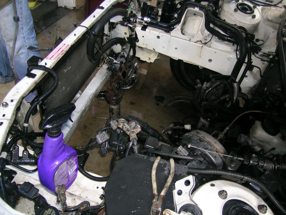 Engine bay with radiator, wiring, and tools. A purple spray bottle is visible