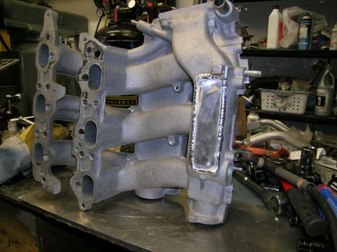 1993 Ford Probe - Intake manifold with visible welding repair on a metal workbench.