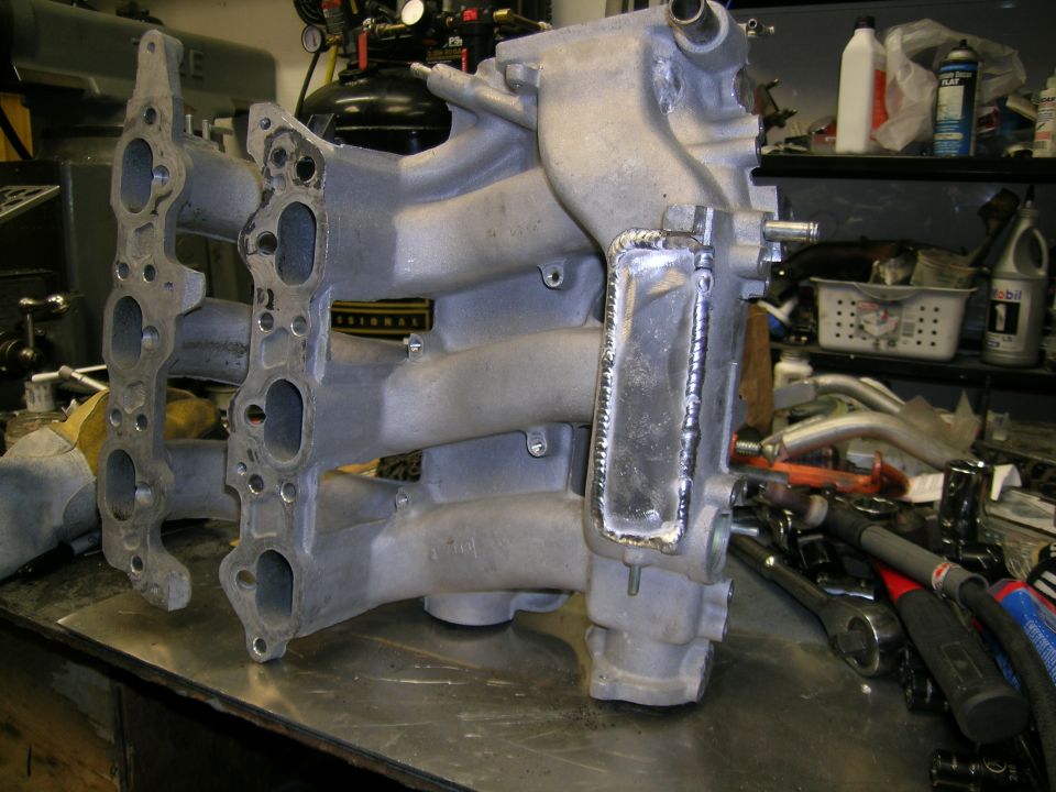Aluminum intake manifold with welded section on a workbench