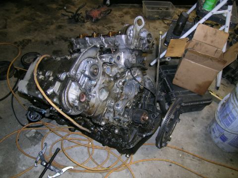 1993 Ford Probe - A disassembled engine rests on the floor amidst various tools and storage containers.