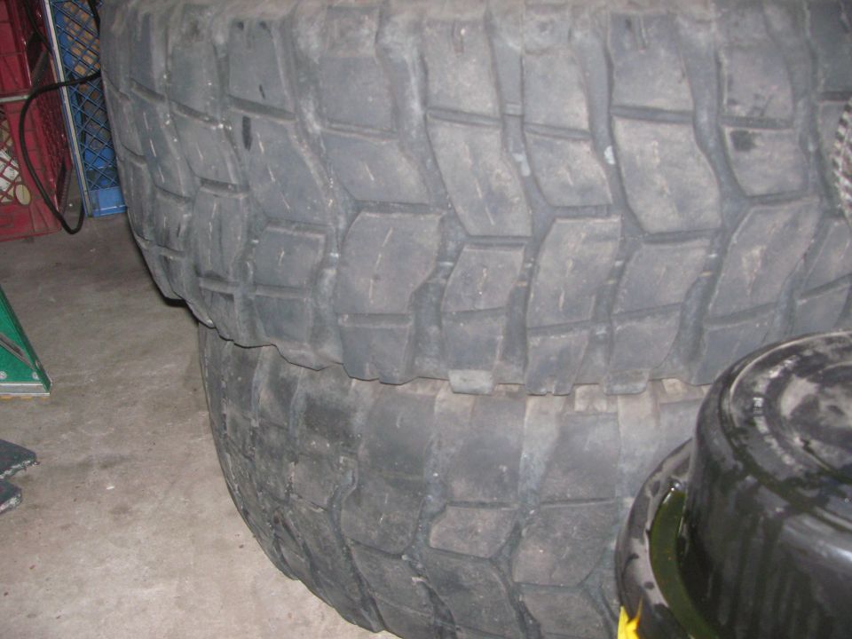 Two large off-road tires stacked on top of each other. Tread pattern is aggressive