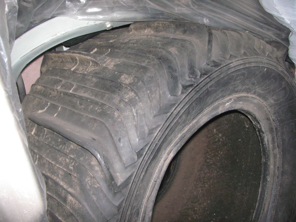 Tractor tire with deep treads, partially covered by plastic sheeting