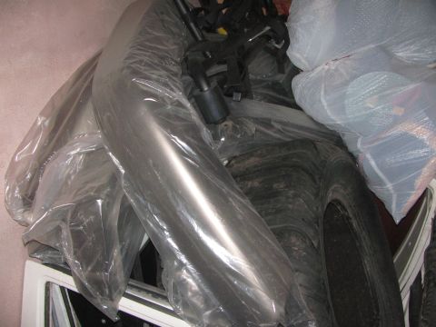 1968 Ford Mustang - Various car parts, including a tire and a metallic component, are stored wrapped in plastic packaging.