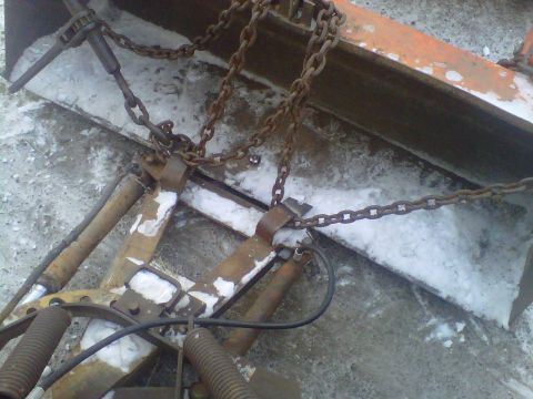 1994 Ford F-150 - This snow plow attachment is covered in rust and connected by chains and hydraulic cylinders.