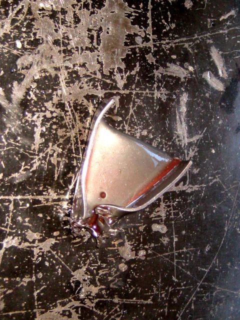 1996 Ford Bronco - Close-up of a chrome trim piece with a red accent, set against a heavily scratched black background.