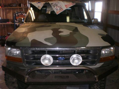 1995 Ford Bronco - Front view of a 1995 Ford Bronco painted in camouflage, parked indoors.
