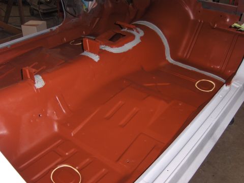 1972 Chevrolet Camaro - Car interior floor pan painted red, showing seam sealer application.