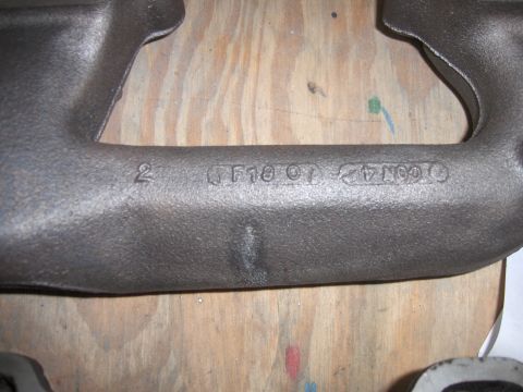 1970 Chevrolet Camaro - A close-up view of a cast iron exhaust manifold shows stamped identification numbers and letters.