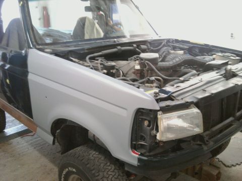 1994 Ford Bronco - The vehicle is undergoing bodywork, with one fender primed and the other still in its original dark blue paint.