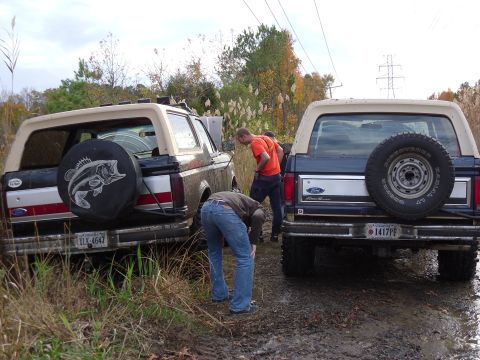 1985 Ford Bronco - Two 1985 Ford Broncos are stuck in the mud off-road.