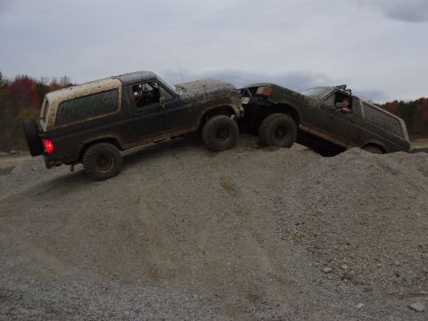 1985 Ford Bronco - Two 1985 Ford Broncos navigate a challenging off-road course on a gravel hill.