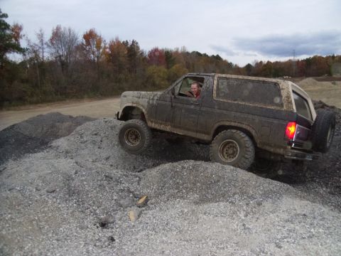 1985 Ford Bronco - This 1985 Ford Bronco navigates a challenging off-road course, its tires kicking up dust and gravel.