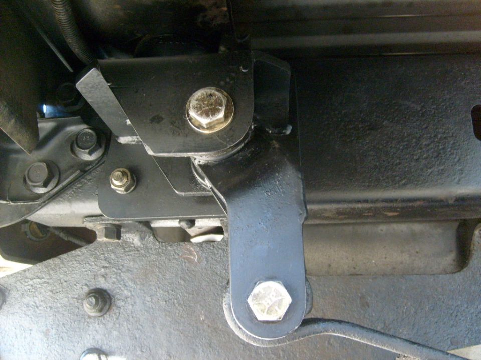 Close-up of a black metal bracket and bolt assembly, likely part of a vehicle's suspension system