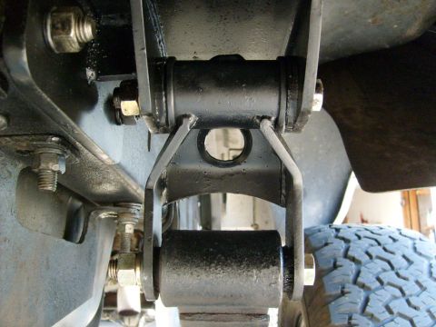 1986 Ford Bronco - Detail of a vehicle's suspension system, focusing on a shackle and bushing assembly.