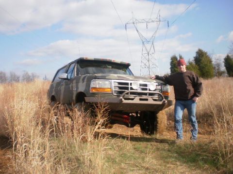 1995 Ford Bronco - A man poses with a lifted, camouflaged 1995 Ford Bronco an aftermarket bumper and off-road tires.