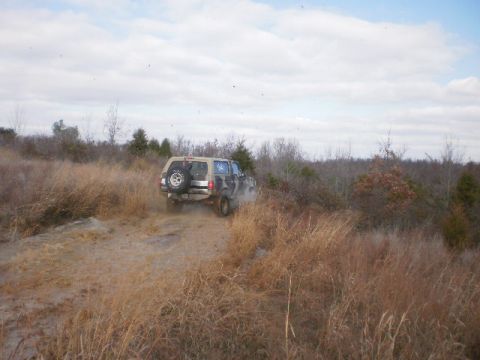 1995 Ford Bronco - Ford Bronco navigates an off-road trail with a spare tire mounted on the rear.