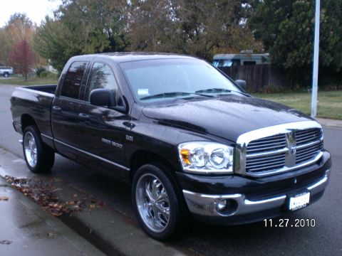 1996 Ford Bronco - Black Dodge Ram 1500 pickup truck with chrome grille and rims parked on a wet street.