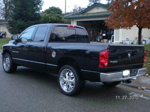 1996 Ford Bronco - A black Dodge Ram pickup truck is parked on a residential street, showing its rear 3/4 profile with custom chrome wheels.