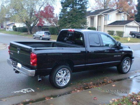 1996 Ford Bronco - A black Dodge Ram pickup truck is parked on a street with houses and trees in the background.
